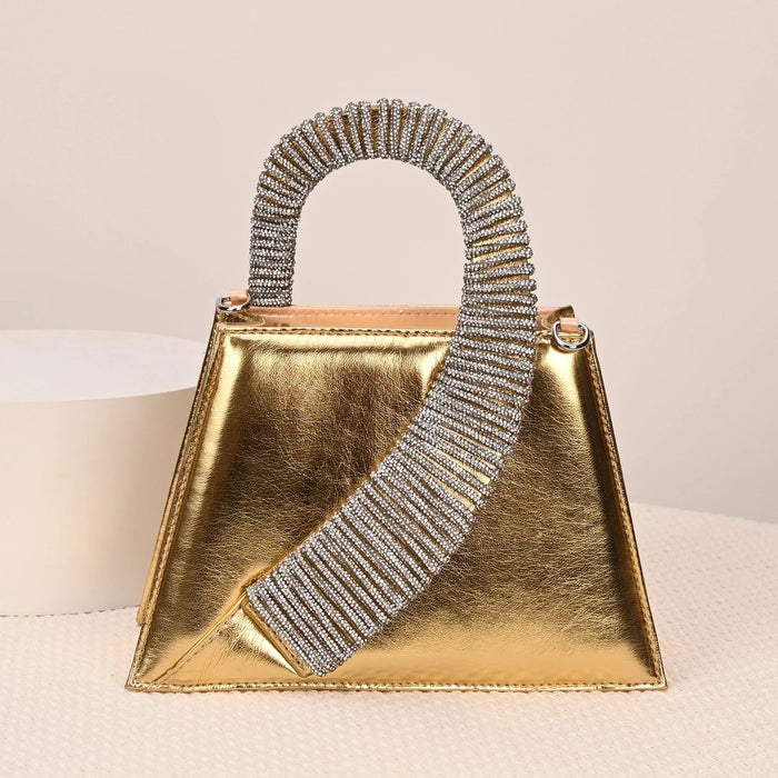 Gold handbag with a sparkling handle on a beige background