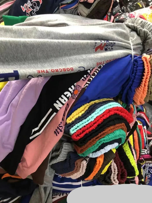 Stack of colorful clothing with visible brand logos in a store setting.
