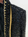 Black sequined jacket with gold trim on a plain background