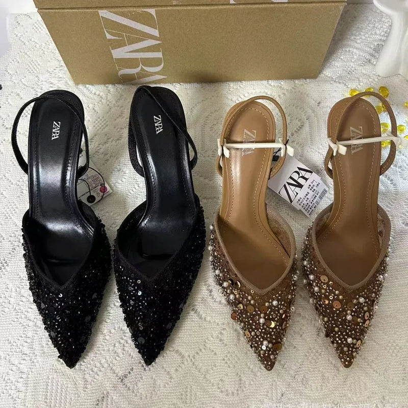 Black and brown pointed-toe shoes with embellishments on a textured surface, Zara box in the background.