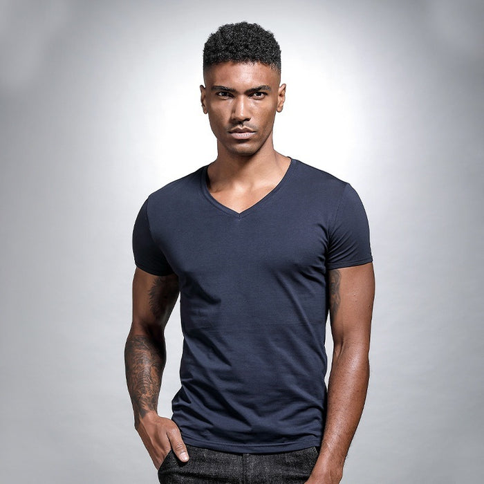 Man wearing a navy blue V-neck t-shirt against a gray background