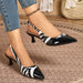 A pair of women's slingback kitten heel pumps with a black and white zebra print and glossy patent black pointed toes, shown being worn with blue jeans on a woven rug.