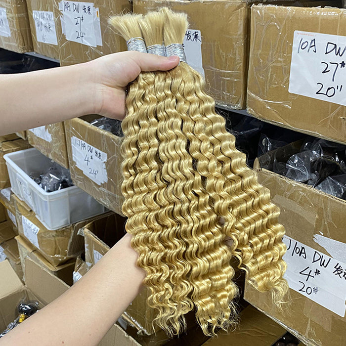 Blonde hair extensions held in front of stacked boxes in a warehouse setting