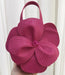 Pink flower-shaped handbag held against a white curtain background