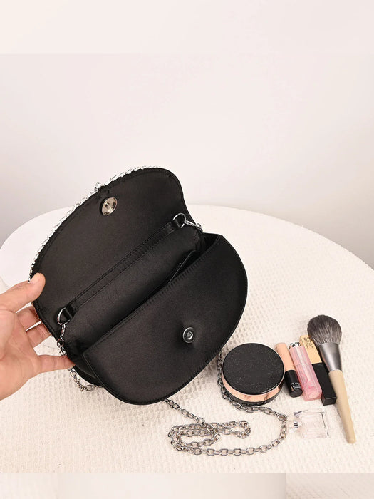 Black handbag with makeup items on a white surface