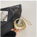 Gold handbag with chain strap held by a hand on a neutral background