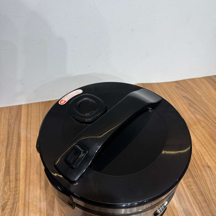 Black trash can with a lid on a wooden surface