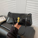 Black handbag with gold clasp held by a hand against a neutral background