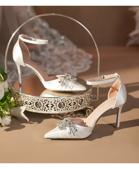 White high-heeled shoes with embellishments on a decorative stand.