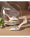 White high-heeled shoes with embellishments on a decorative stand.