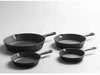 Set of four black frying pans on a light gray background
