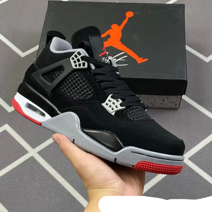 Black and red sneaker held in hand with Jordan brand box in the background