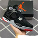 Black and red sneaker held in hand with Jordan brand box in the background