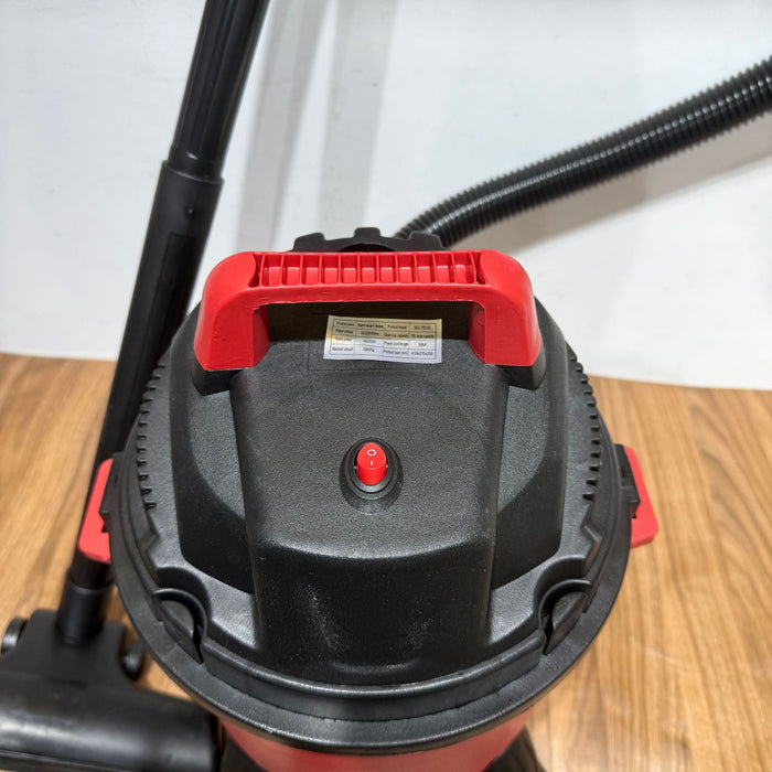 Close-up of a red and black vacuum cleaner on a wooden floor.