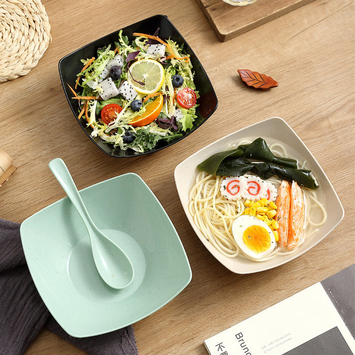 Two bowls of food on a wooden table with a green plate and spoon.