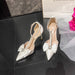 White high-heeled shoes with decorative bows on a dark surface