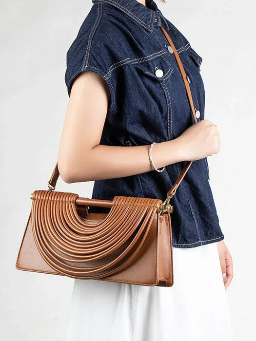 Person holding a brown handbag with a white background