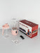 Pink portable juicer with clear container, packaging, and USB cable on a white background
