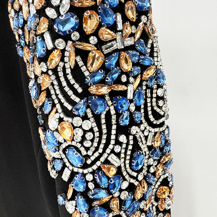 Close-up of a dress with intricate beadwork featuring blue, gold, and silver colors on a plain background.