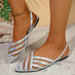 Silver strappy sandals worn on feet with a neutral background