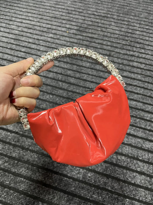 Red handbag with a decorative headband held by a hand on a textured gray background