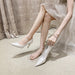 Person wearing white high-heeled shoes with a light background
