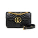 Black quilted handbag with gold chain and logo on a white background