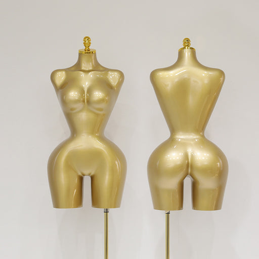 Two gold mannequins on stands against a gray background
