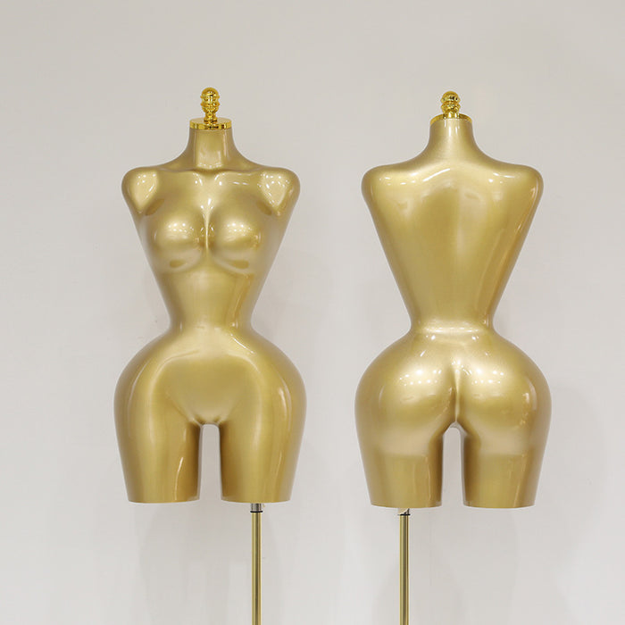 Two gold mannequins on stands against a gray background