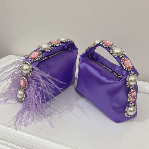 Two purple handbags with decorative handles featuring pearls and feathers on a white surface.