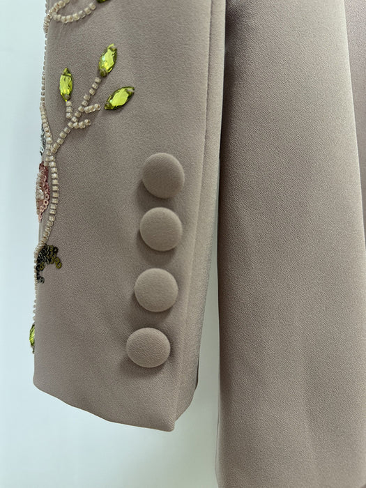 Close-up of a beige coat with decorative buttons and beadwork on a light blue background