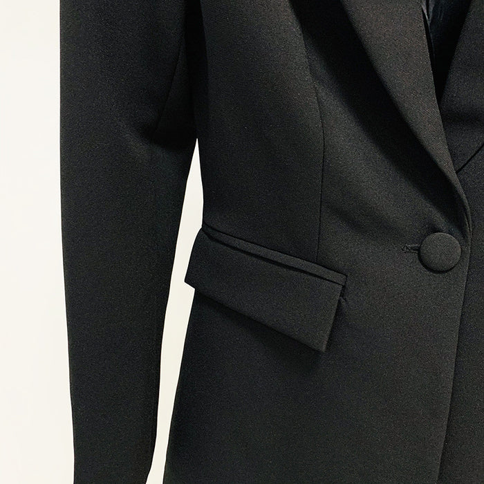 Close-up of a black suit jacket with a button and pocket on a white background