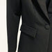 Close-up of a black suit jacket with a button and pocket on a white background