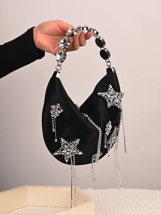 Black handbag with star-shaped embellishments held by a hand against a neutral background