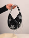 Black handbag with star-shaped embellishments held by a hand against a neutral background