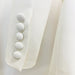Close-up of a white blazer with button details on a light gray background