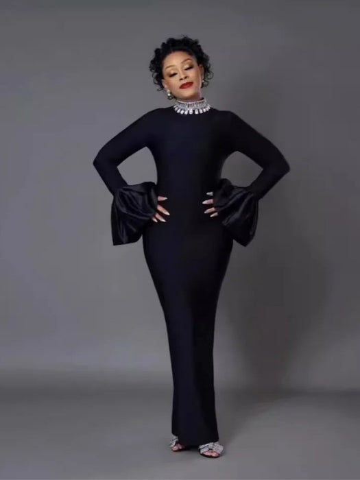 A woman wearing a black long-sleeve dress with a round neckline and a high waist, featuring a solid color with a zipper at the placket.