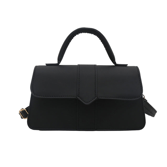A black structured handbag with a top handle, a front flap, and a small gold-tone buckle detail on the side, shown against a plain white background.