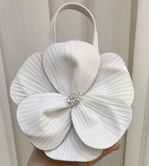 White handbag with a large floral design held against a neutral background