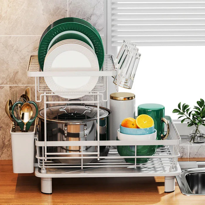Dish drying rack with green plates, cups, and utensils on a kitchen counter.