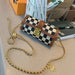 Checkered handbag with gold chain on a desk