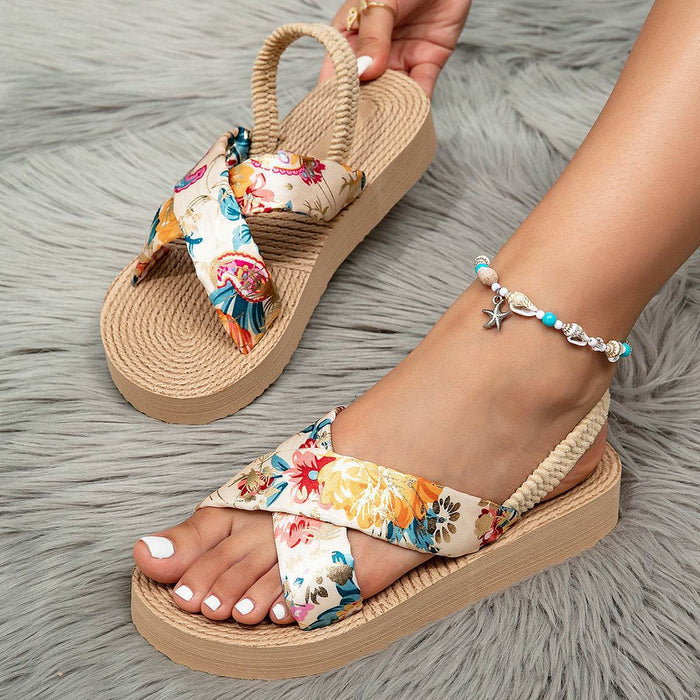 Floral sandals with woven straps worn on a gray textured surface