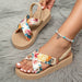 Floral sandals with woven straps worn on a gray textured surface