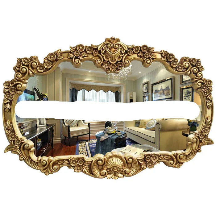 Decorative gold mirror with intricate designs reflecting a living room.