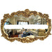 Decorative gold mirror with intricate designs reflecting a living room.