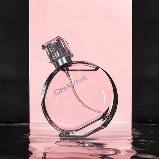 Perfume bottle with 'CHAVAN' branding on a reflective surface with a pink background