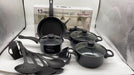13-piece cookware set with black pots, pans, and utensils on a white surface.
