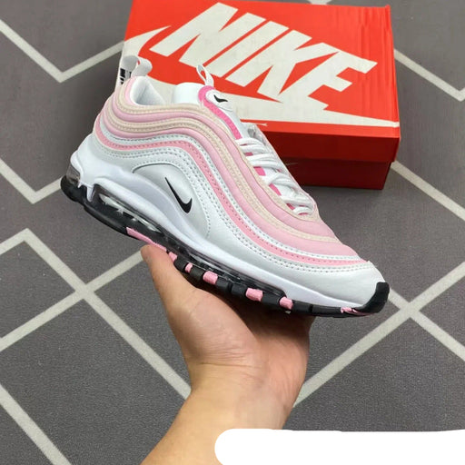 Pink and white sneaker held in front of a red Nike box on a tiled floor.