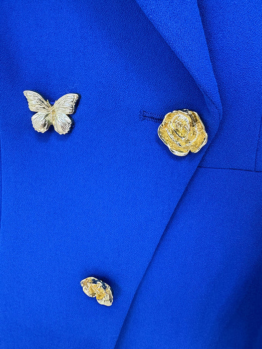 Gold butterfly and rose brooches on a blue fabric background