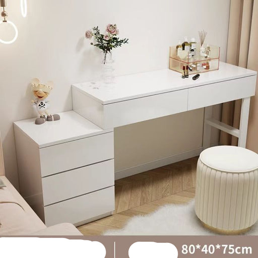 White vanity table with drawers and a small stool in a room setting.